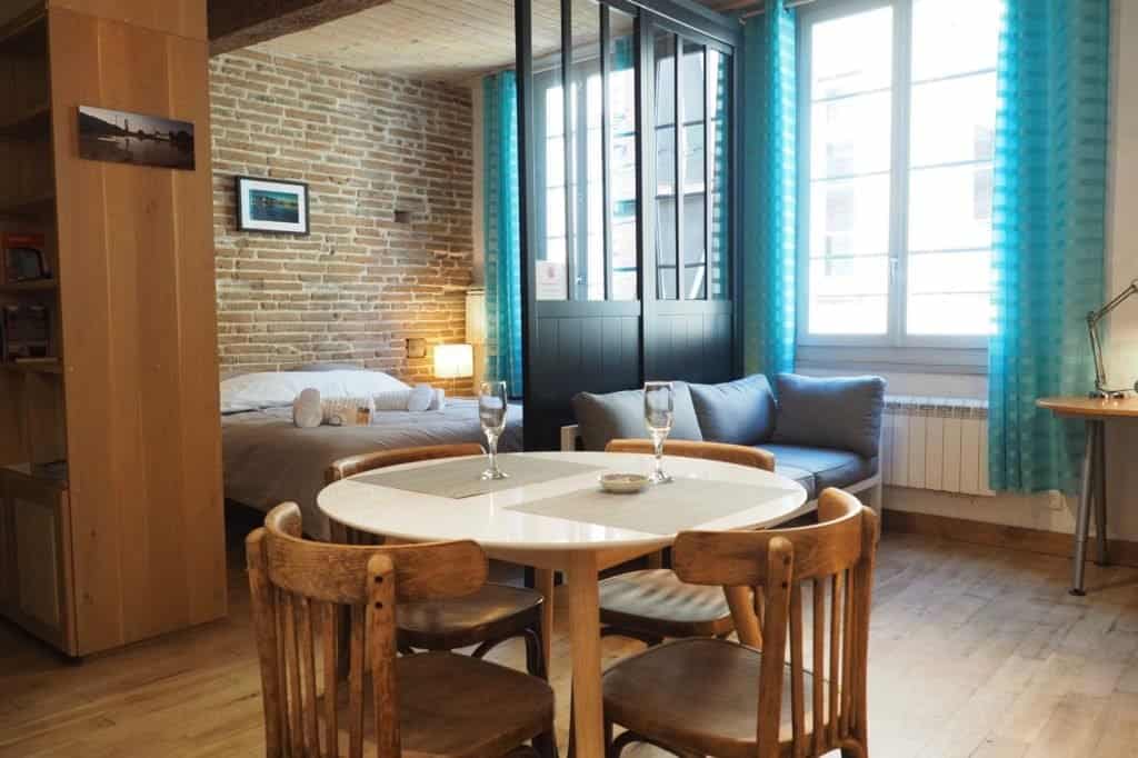 Holiday home in Toulouse: cosy interior with exposed wooden beams, traditional bricks, designer furniture